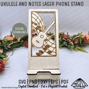 May include: A wooden laser-cut phone stand featuring a ukulele and musical notes design. The stand has a rectangular frame with a cutout of a ukulele and musical notes. The text "UKULELE AND NOTES LASER PHONE STAND" is at the top. The stand is a digital download.