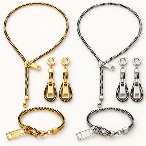 May include: Two jewelry sets, one gold-toned and one silver-toned, each consisting of a necklace, a bracelet, and a pair of drop earrings. Each piece is designed to resemble a zipper, featuring interlocking teeth, a pull tab, and a slider.