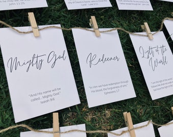 May include: A set of five white cards with black text, each card featuring a different title and scripture verse. The titles are "Mighty God", "Redeemer", "Light of the World", "The Way", and "The Truth". The cards are hung on a string with clothespins.