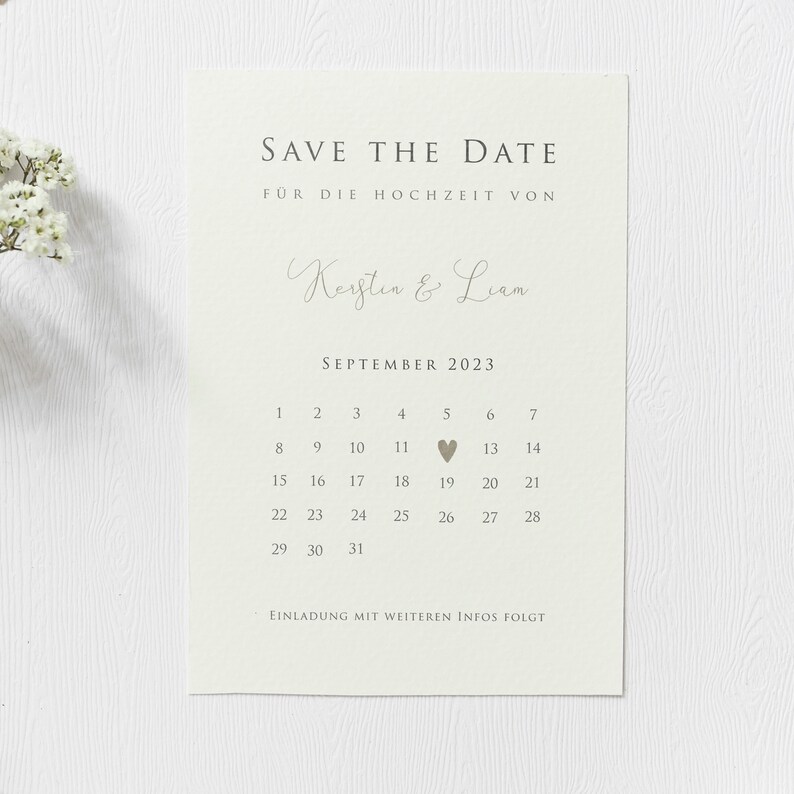 May include: Save the date card with a calendar for September 2023. The date September 19th is highlighted with a small heart. The card is beige with brown text and reads "Save the Date" and "For the wedding of Kerstin & Liam".