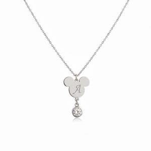 Peut inclure: Un collier argent&eacute; avec un pendentif en forme d'oreilles de Mickey Mouse, grav&eacute; de la lettre "A". Une petite pierre pr&eacute;cieuse ronde et transparente est suspendue en dessous. La cha&icirc;ne du collier est &eacute;galement argent&eacute;e.
