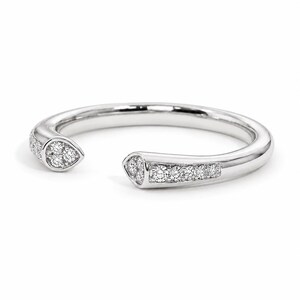 May include: A silver-toned open ring featuring a polished band with two tapered ends. Each end is set with small, clear, round-cut stones, with three stones clustered at the tips and a row of five stones extending along the band's shank.