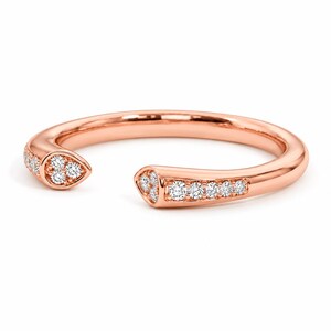 May include: A rose gold open-style ring featuring a polished band with two tapered ends. Each end is set with a cluster of small, round, clear white diamonds, with additional diamonds embedded along the sides of the band near the opening.