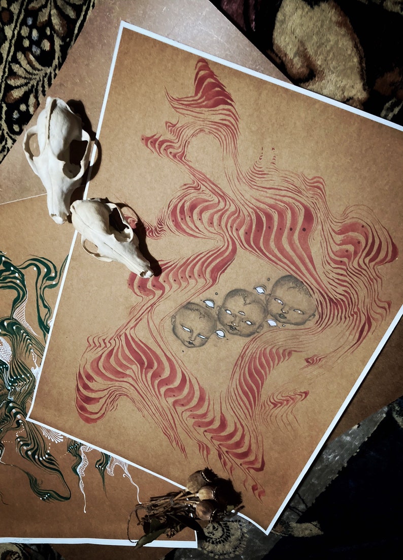 May include: A brown paper print with red and white lines and a pattern of four faces with closed eyes. The faces are drawn in black and white and are surrounded by a swirling pattern of red and white lines.