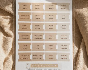 May include: A sheet of adhesive Bible index tabs in various shades of beige and tan. The tabs are arranged in six rows and four columns, each labeled with the names of Old Testament books. At the bottom, the text reads SALTLIGHT and a quote.