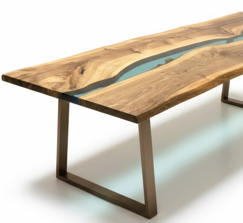 Puede incluir: Una mesa de comedor rectangular con dos tablones de madera de borde natural unidos por un r&iacute;o central de resina azul claro transl&uacute;cida. La mesa se apoya sobre dos patas met&aacute;licas en forma de U con acabado en bronce mate.