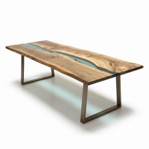 Puede incluir: Una mesa de comedor rectangular con un tablero de madera de nogal de borde natural y una incrustaci&oacute;n sinuosa de resina azul claro que recorre el centro. La mesa se apoya sobre dos patas met&aacute;licas oscuras en forma de U.