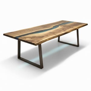 Puede incluir: Una mesa de comedor rectangular con una superficie de madera de borde natural y una incrustaci&oacute;n central de resina azul transl&uacute;cida. La mesa se apoya sobre dos patas de metal oscuro en forma de U, creando una base estable.