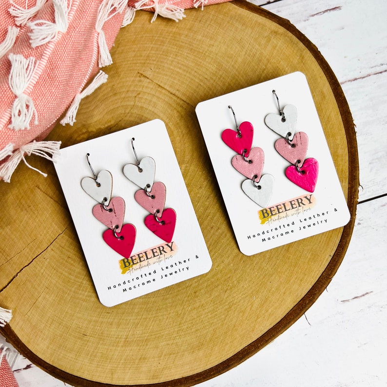 May include: Two pairs of pink, white, and red layered heart earrings on white cards with the text "BEELERY Handmade with love Handcrafted Leather & Macrame Jewelry".