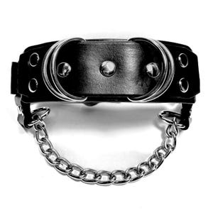 May include: Black leather collar with two silver rings and silver studs. A silver chain is attached to the collar.