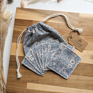 May include: A set of 14 reusable cotton rounds in a floral print fabric, with a drawstring bag and a tag that reads "Econabee Handmade Reusable Eco Products".
