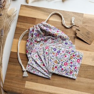 May include: A set of reusable cotton rounds in a floral print fabric, with a drawstring bag. The bag is made of the same fabric and has a tag that reads "Econabee Handmade Reusable Eco Products".