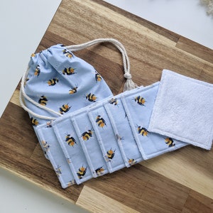 May include: Set of reusable makeup remover pads with a bee print, in a blue drawstring bag. The pads are made of soft, absorbent fabric and are perfect for removing makeup and cleansing the skin.