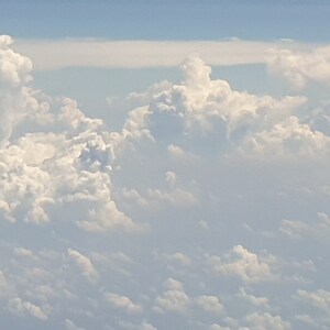 May include: A view of fluffy white clouds against a light blue sky. The clouds are arranged in a variety of shapes and sizes, creating a beautiful and serene scene.