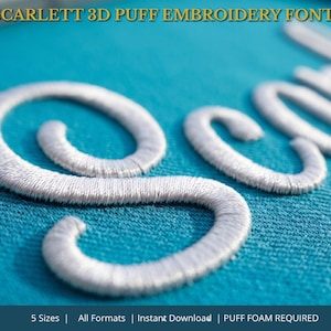 Könnte beinhalten: Nahaufnahme von weißem gesticktem Text auf türkisfarbenem Stoff. Der Text lautet "Scarlett" in einer 3D-Puff-Stickschrift. Das Bild enthält auch den Text "BX FORMAT" in einem goldenen Kreis und weitere Details zur Schrift.
