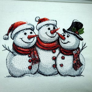 Op de afbeelding: Geborduurd beeld van drie sneeuwmannen. Elke sneeuwman heeft een wortelneus, een rode sjaal en een hoed. Eén sneeuwman draagt een hoge hoed met hulst. De sneeuwmannen lachen en hebben takkenarmen.