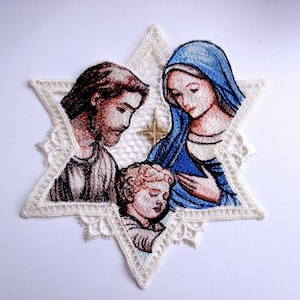 Peut inclure: Image brodée de la Sainte Famille, Marie, Joseph et l'enfant Jésus, dans un cadre en dentelle blanche en forme d'étoile. L'image est de style vintage avec une étoile dorée au-dessus de la famille.