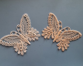 May include: Two white lace butterfly appliques with intricate details. The butterflies are delicate and have a vintage feel.