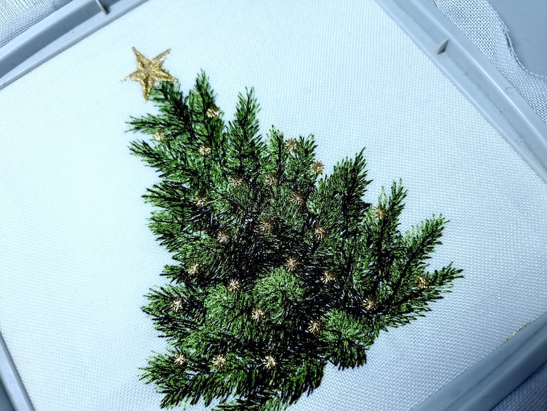 May include: Embroidered Christmas tree with a gold star on top. The tree is green and has gold accents.