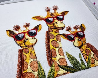 Maschinenstickerei-Giraffen mit flauschigen Mähnen und Sonnenbrillen. Maschinenstickmotive mit Tiermotiven. 4 Größen.