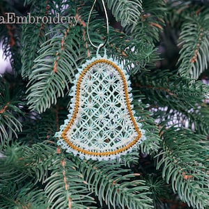 以下が含まれることがあります： 緑の松の枝に、繊細なレース模様の白と金のベルのオーナメントがぶら下がっています。Lira Embroidery.