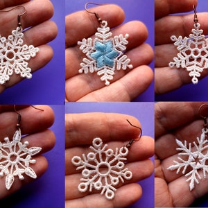 May include: Six pairs of snowflake earrings. Each pair features a delicate white lace snowflake design. One pair has a blue snowflake in the center.