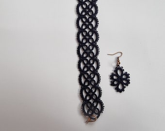 May include: A black lace choker necklace and matching earrings. The necklace is a long, thin strip of lace with a delicate floral pattern. The earrings are small and dangle from a simple hook.