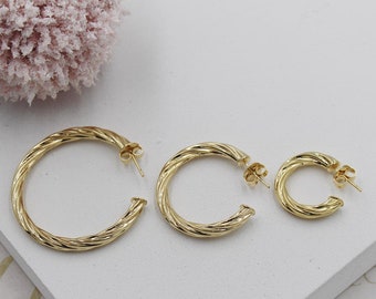 May include: Three gold hoop earrings with a twisted design. The earrings are of different sizes.
