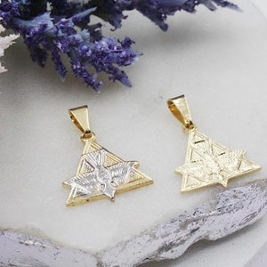May include: Two gold pendants with a silver dove design inside a triangle shape. The pendants are on a white surface.