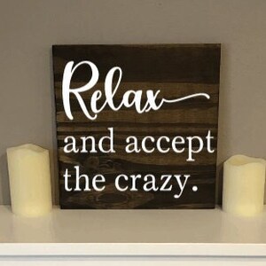 May include: A wooden sign with the text "Relax and accept the crazy." in white lettering on a dark brown background.