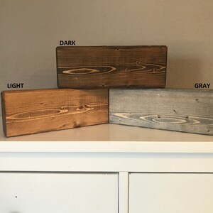 Pode incluir: Tr&ecirc;s t&aacute;buas de madeira manchadas em cores diferentes: marrom escuro, marrom claro e cinza. As t&aacute;buas s&atilde;o etiquetadas como "DARK", "LIGHT" e "GRAY".