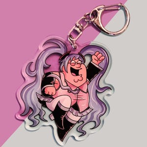 May include: A clear acrylic keychain featuring a cartoon character with purple hair, wearing a pink and black outfit, and a large grin. The character is holding a microphone and has a large, round belly.