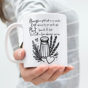 K&ouml;nnte beinhalten: Eine wei&szlig;e Keramiktasse mit einer schwarz-wei&szlig;en Illustration eines Salzstreuers, Rosmarins und Lavendels. Der Text auf der Tasse lautet "Always store spilled salt over your shoulder Keep rosemary by your garden gate Plant lavender for luck And Fall in love whenever you can".