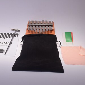 An image of everything that is included in the package. A carrying case, kalimba thumb piano, tuning hammer, cleaning kit, finger protector, and a thumb piano study guide.