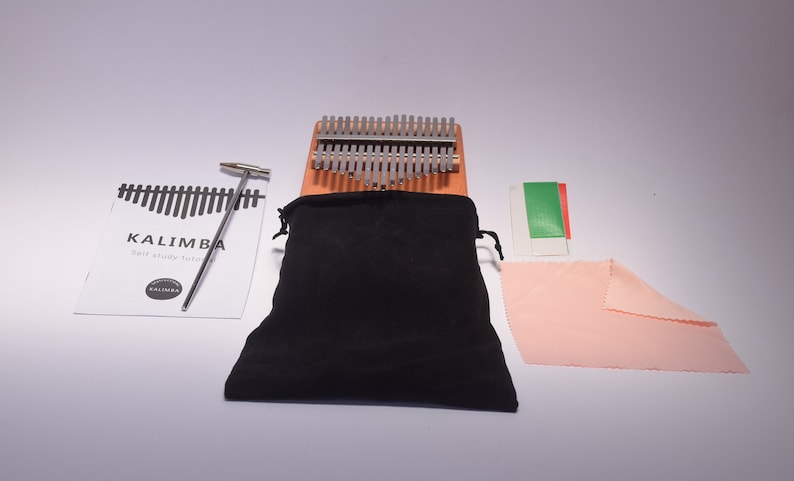 An image of everything that is included in the package. A carrying case, kalimba thumb piano, tuning hammer, cleaning kit, finger protector, and a thumb piano study guide.