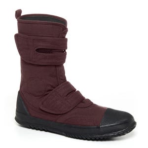May include: A burgundy canvas boot with a black rubber sole and toe cap. The boot features three adjustable hook-and-loop straps for closure and a padded collar. The design is a high-top style, suitable for various activities.