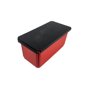 May include: A rectangular red container with a black lid. The container has a smooth, glossy finish and a black lid that covers the top. The lid appears to be made of a textured material.