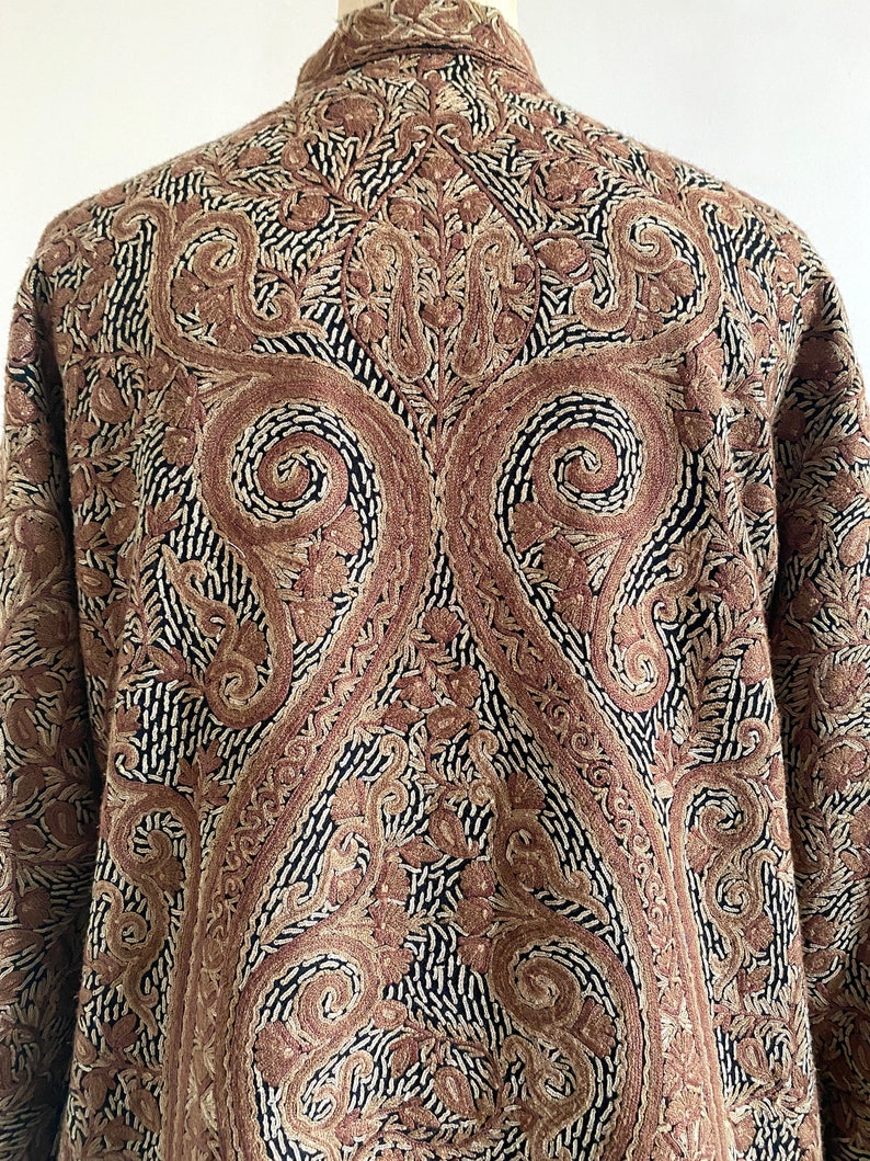 May include: A brown and black paisley patterned jacket with a collar and long sleeves.