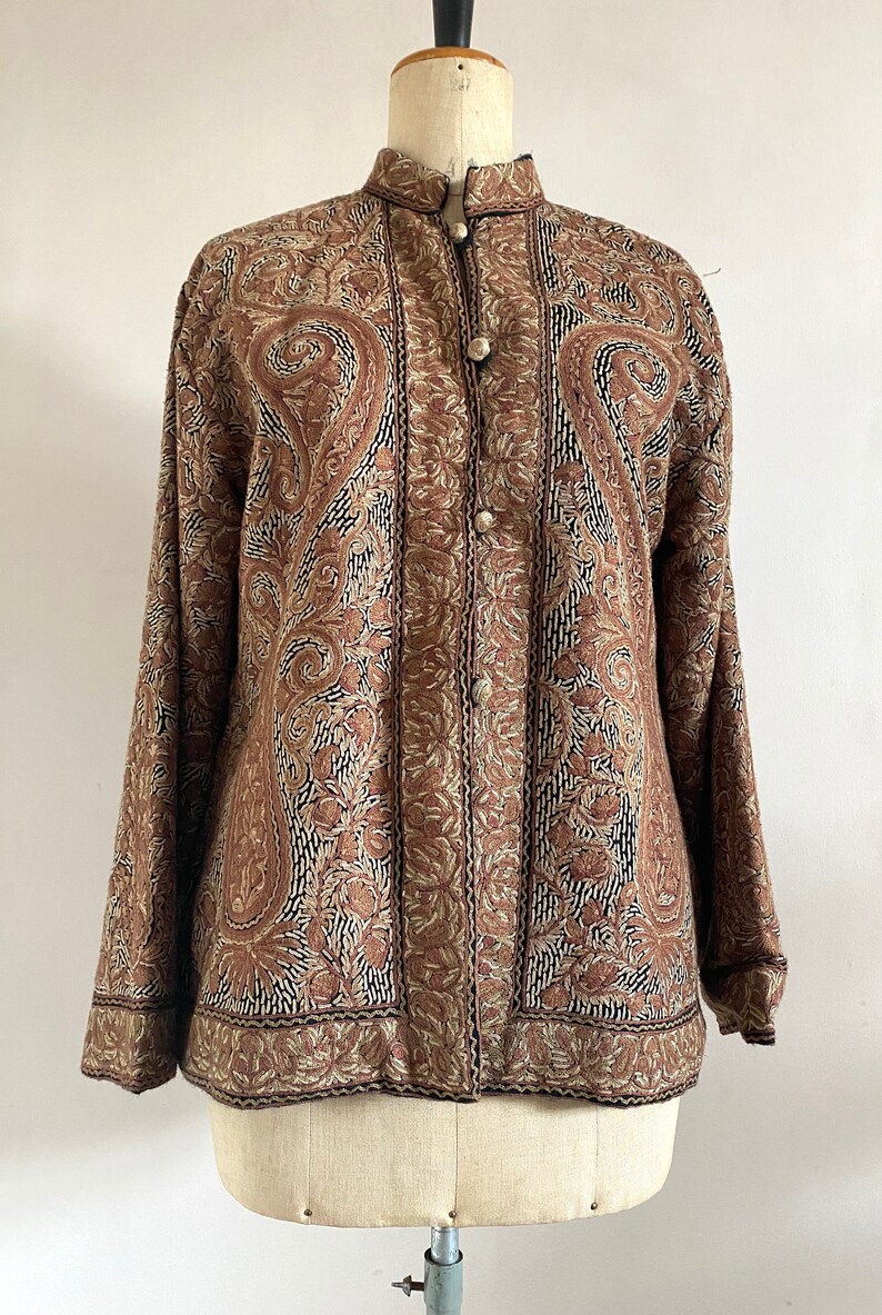 May include: A brown embroidered jacket with a paisley pattern and button closure.