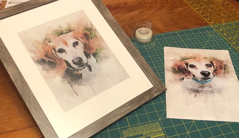 May include: A framed watercolor painting of a dog with brown and white fur. The dog is looking directly at the camera. The painting is on a white mat and has a gray wood frame.