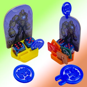 May include: Two 3D printed game pieces with blue and red dice. The pieces are made of yellow and orange plastic and feature a card with a stone giant illustration. The pieces are for a tabletop game.
