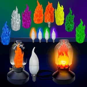 May include: A collection of flame-shaped LED light bulbs in various colors, including blue, purple, orange, and green. The image also shows several flame-shaped bulbs and two black lamps with glass covers, each with a flame-shaped bulb inside.