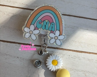 May include: A rainbow-colored badge reel with a white daisy charm and a yellow bead. The rainbow has the letters "CNA" in the center.