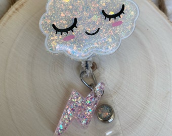 Può includere: Un portabadge a forma di nuvola bianca glitterata con un viso sorridente, occhi chiusi e guance rosa. Un piccolo ciondolo a forma di fulmine rosa glitterato pende dalla nuvola tramite un anellino di metallo. Con cinturino in plastica trasparente.