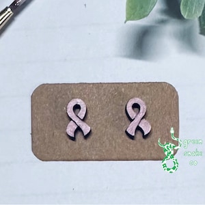 May include: A pair of pink wooden ribbon earrings on a brown card with the text "green snake go" printed on it.