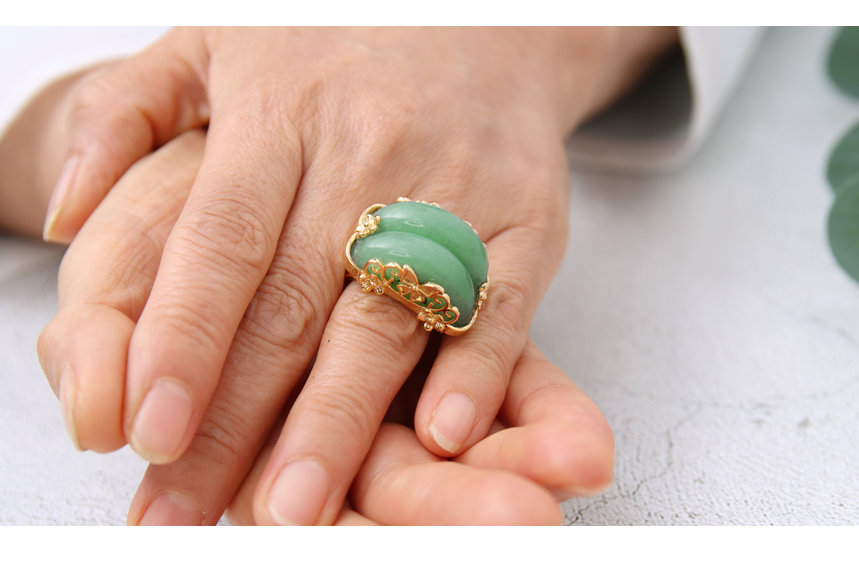 K&ouml;nnte beinhalten: Ein goldener Ring mit einem gr&uuml;nen Jade-Stein, der in einem floralen Design gefasst ist.