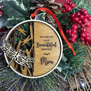 May include: Wooden Christmas ornament with a dragonfly cutout and the text "You are my most beautiful memory. Mom".