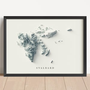 May include: Framed art print featuring a 3D topographical map of Svalbard in shades of gray and white. The map is set against a cream background, with the word "SVALBARD" printed in a simple font below the map. The print is encased in a black frame.