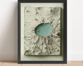 May include: A framed vintage map of Crater Lake National Park in Oregon. The map shows the lake, surrounding mountains, and nearby towns. The map is printed in shades of green, brown, and blue.