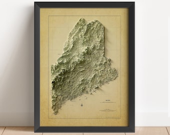 May include: A framed vintage-style topographic map of the state of Maine. The map is in shades of green and brown, with a raised 3D effect. The map is framed in black and has a white background.